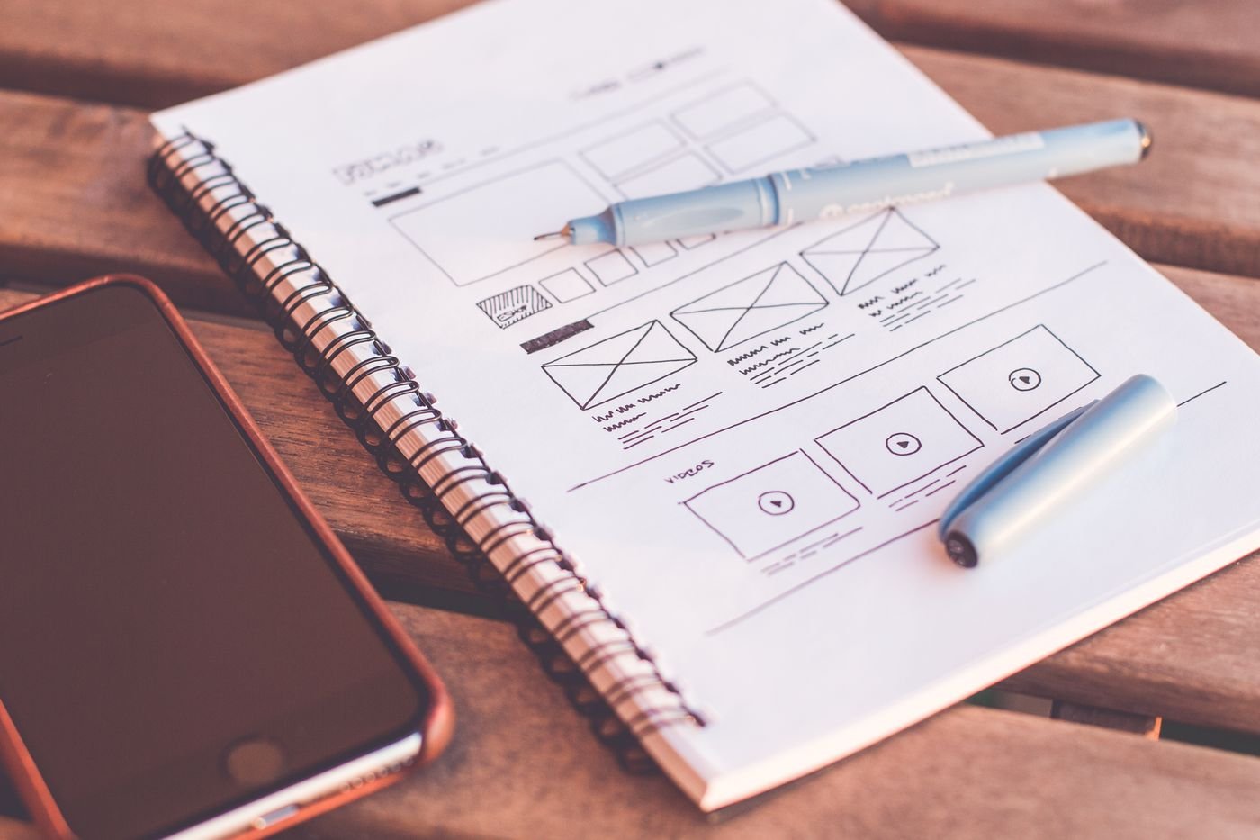 Boceto de wireframe para diseño de página web junto a un teléfono
